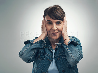 Buy stock photo Studio portrait of a senior woman covering her ears against a grey background
