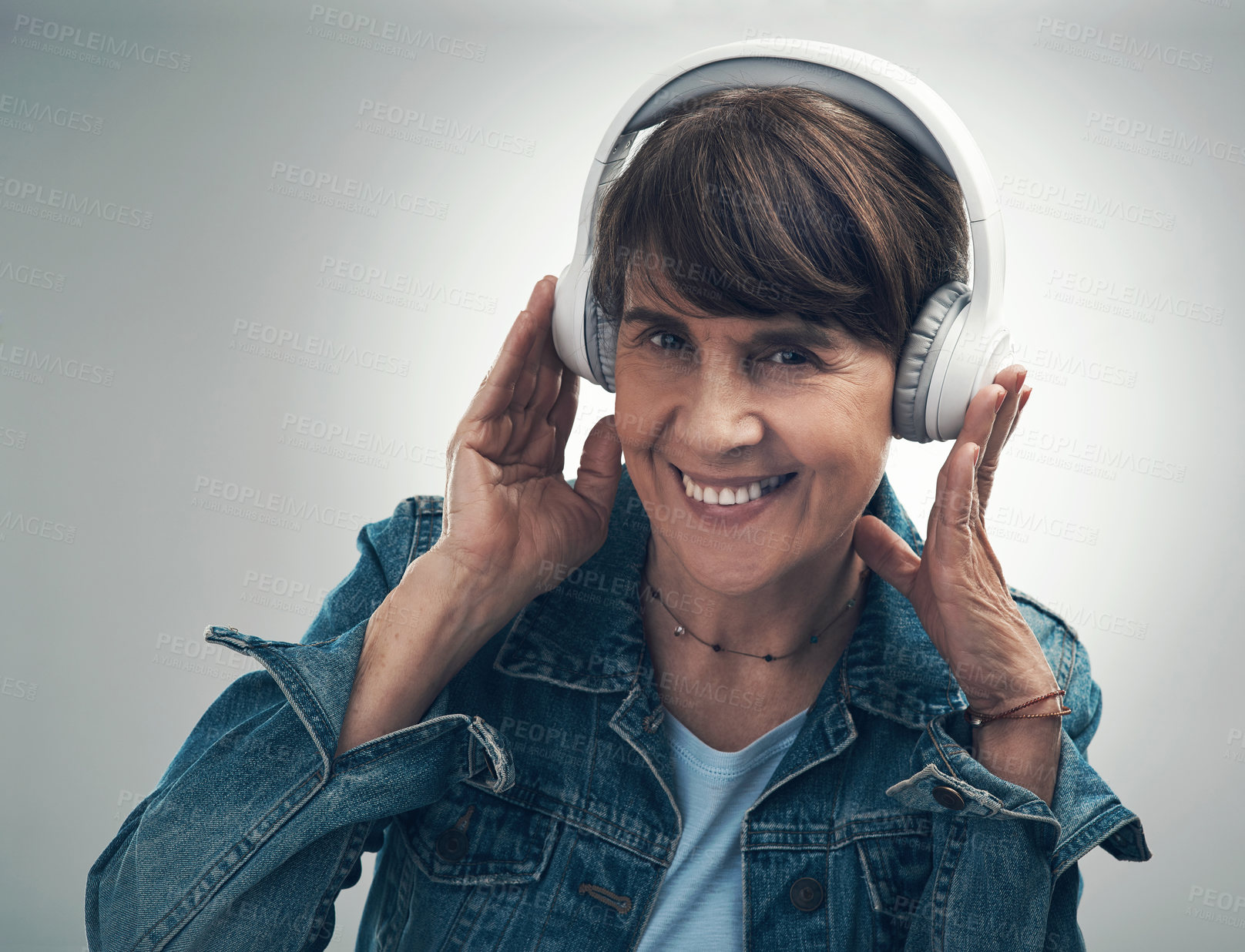 Buy stock photo Studio portrait of a senior woman wearing headphones against a grey background