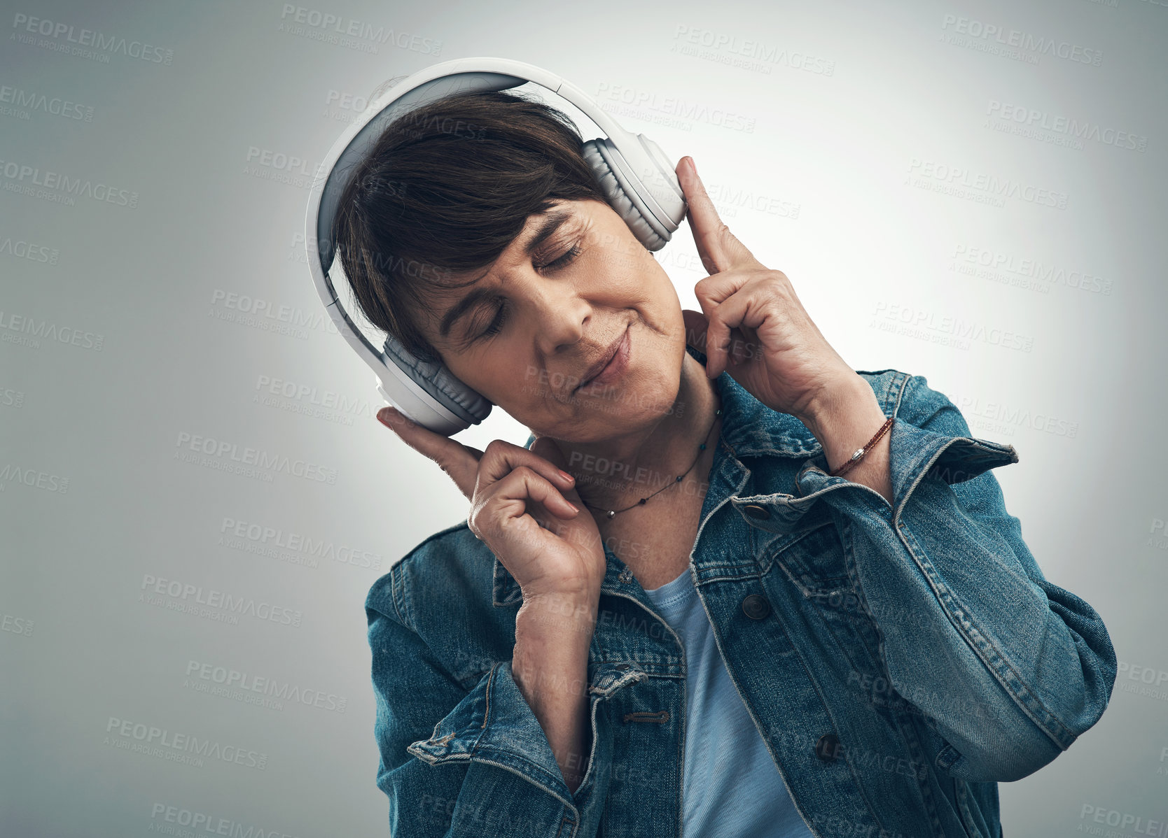 Buy stock photo Studio shot of a senior woman wearing headphones against a grey background