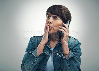 Buy stock photo Studio shot of a senior woman looking shocked while talking on a cellphone against a grey background