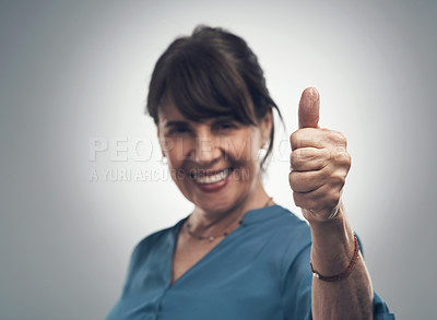 Buy stock photo Studio portrait of a senior woman showing thumbs up against a grey background