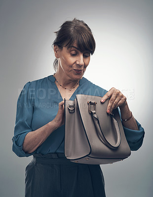 Buy stock photo Studio shot of a senior woman looking for something in her handbag against a grey background