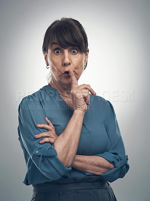 Buy stock photo Studio portrait of a senior woman posing with her finger on her lips against a grey background