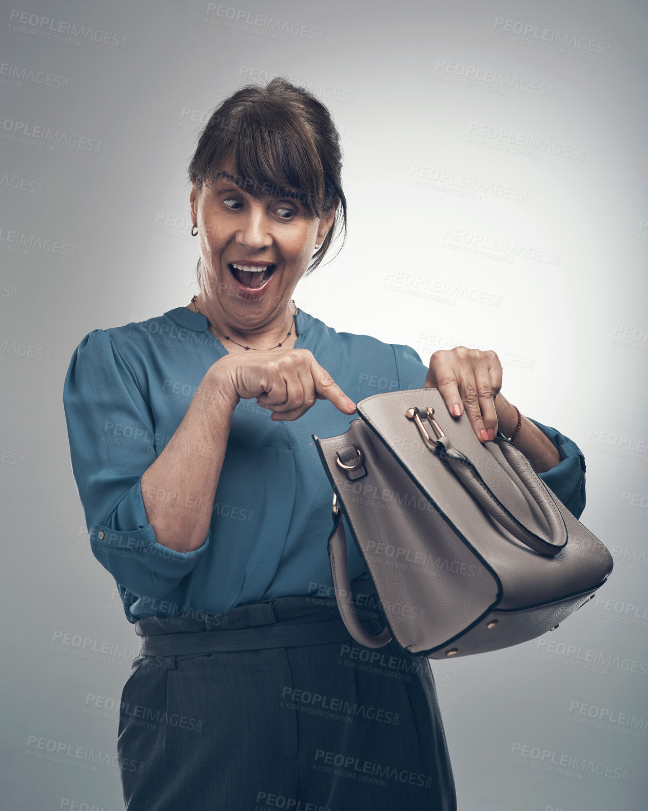 Buy stock photo Studio shot of a senior woman looking for something in her handbag against a grey background