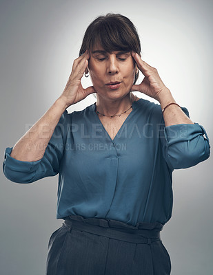 Buy stock photo Studio shot of a senior woman experiencing a headache against a grey background