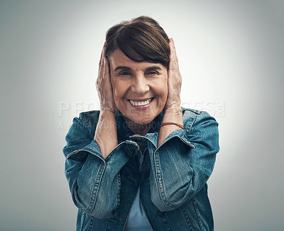 Buy stock photo Studio portrait of a senior woman covering her ears against a grey background