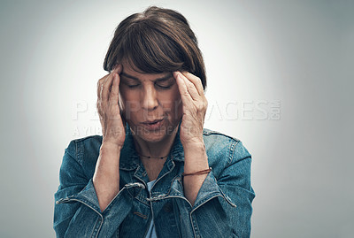 Buy stock photo Studio shot of a senior woman experiencing a headache against a grey background