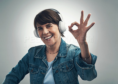 Buy stock photo Studio portrait of a senior woman making an okay gesture while wearing headphones against a grey background