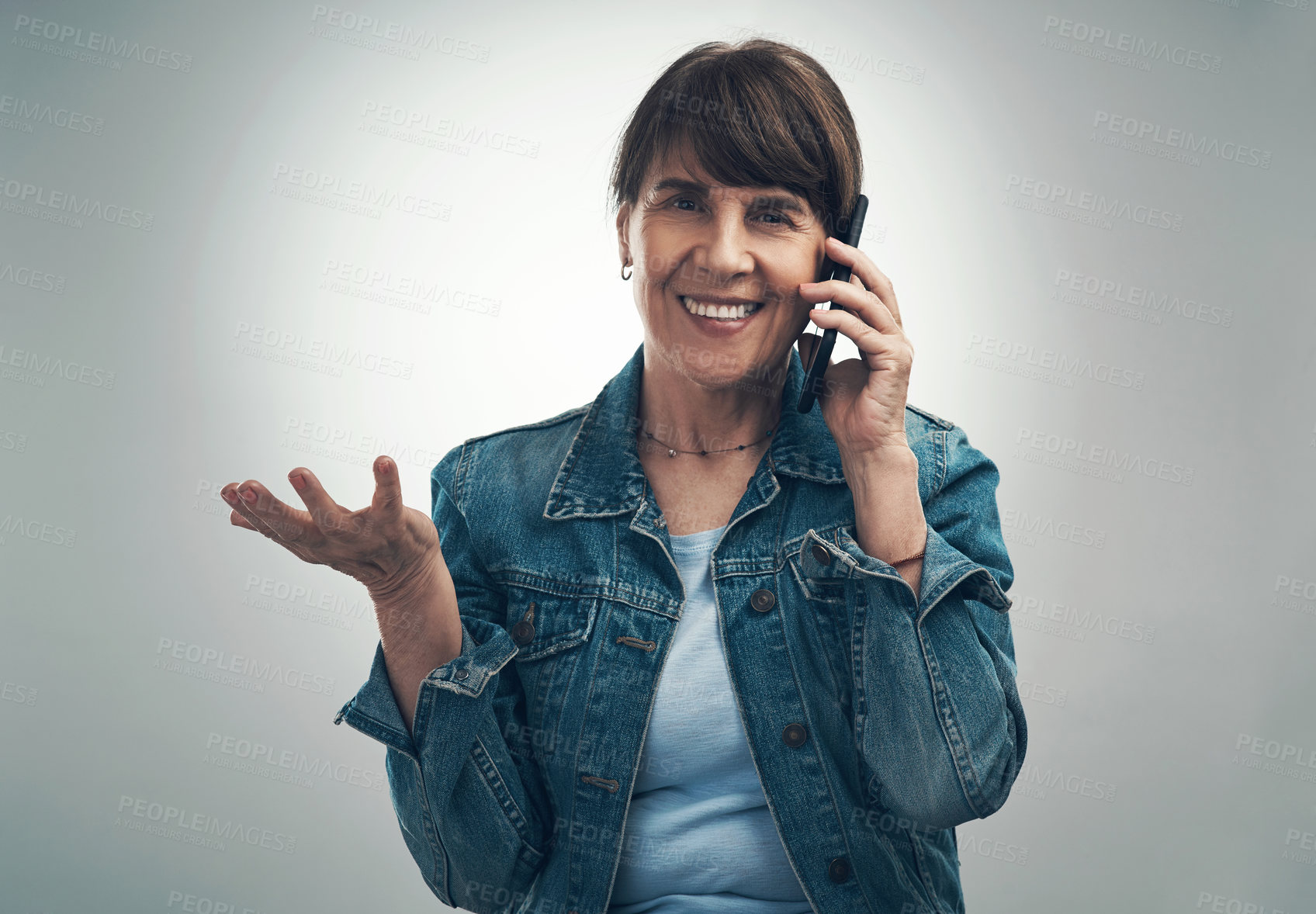 Buy stock photo Studio portrait of a senior woman talking on a cellphone against a grey background