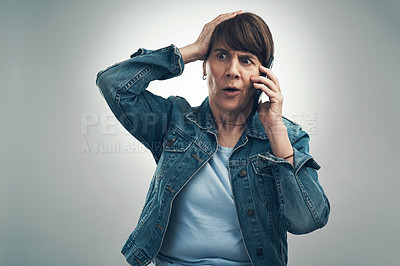 Buy stock photo Studio shot of a senior woman looking shocked while talking on a cellphone against a grey background