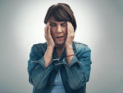 Buy stock photo Studio shot of a senior woman experiencing a headache against a grey background