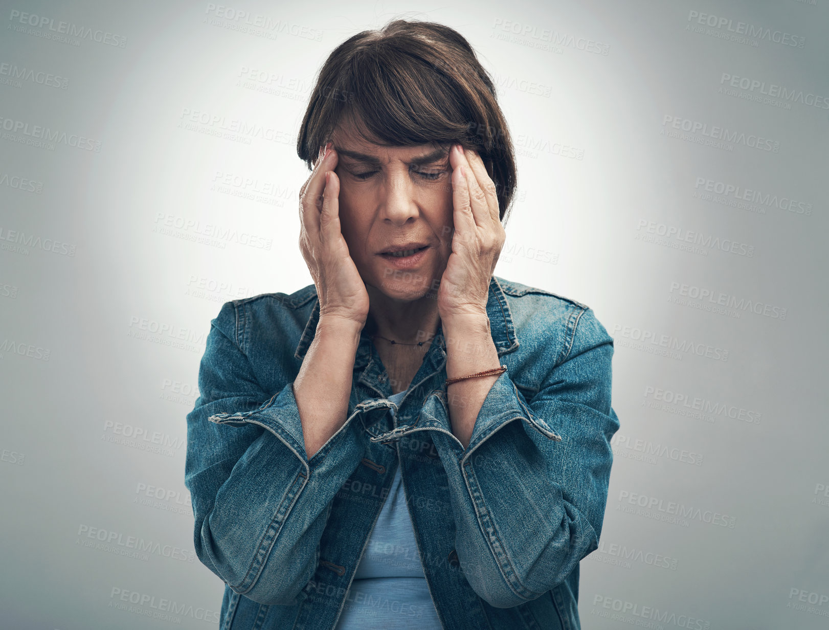 Buy stock photo Studio shot of a senior woman experiencing a headache against a grey background