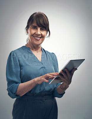 Buy stock photo Studio portrait of a senior woman using a digital tablet against a grey background