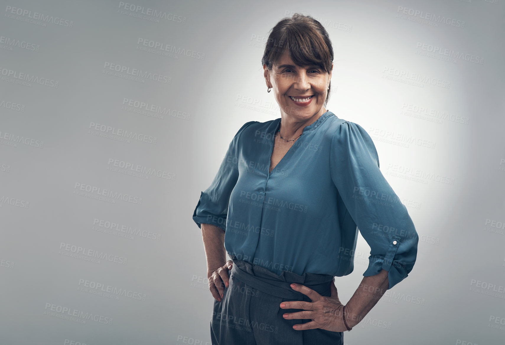 Buy stock photo Studio portrait of a senior woman standing with her hands on her hips against a grey background