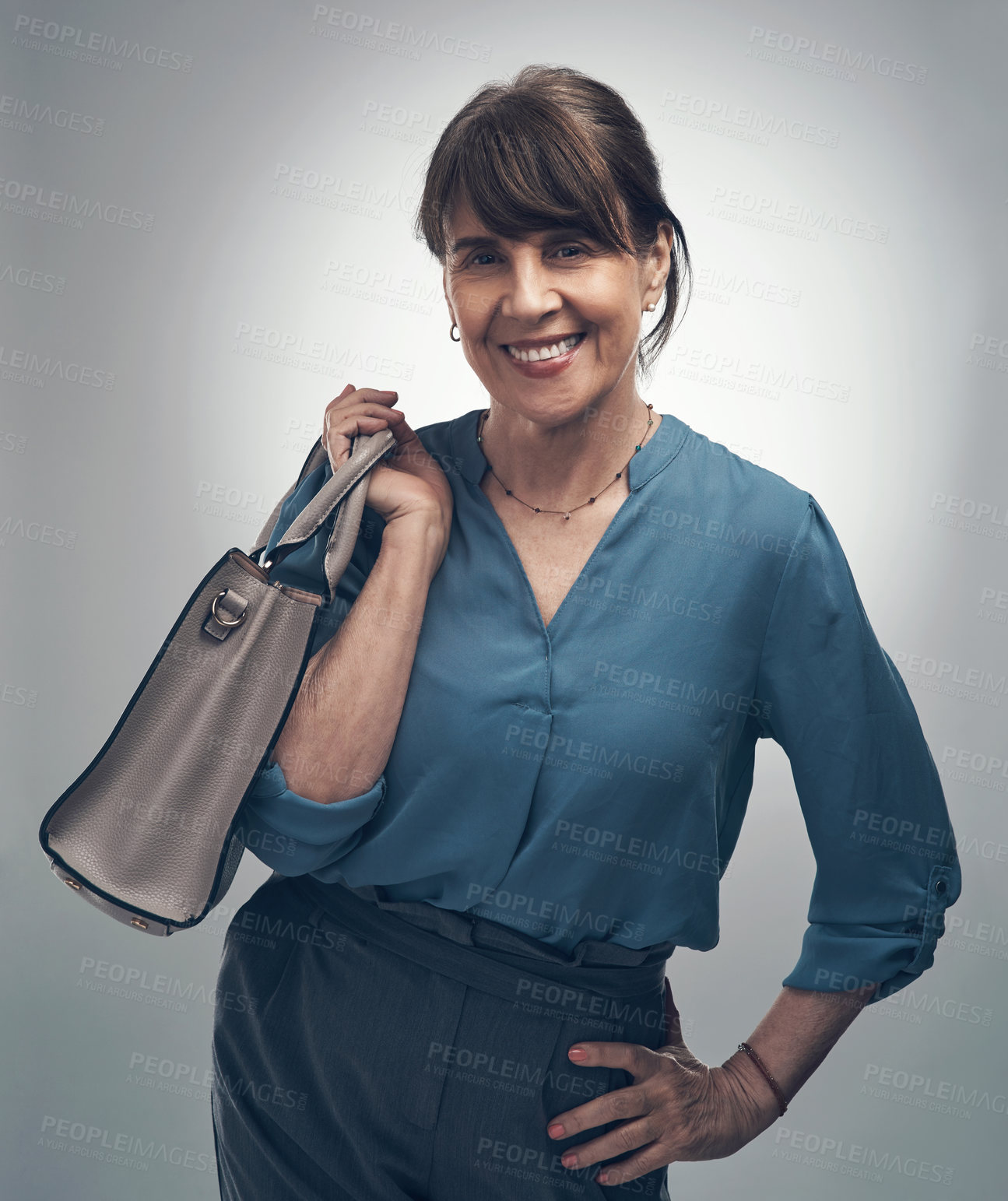 Buy stock photo Studio portrait of a senior woman holding a handbag against a grey background