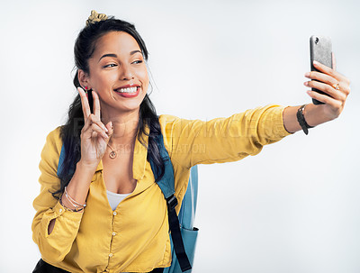 Buy stock photo Studio shot of a woman wearing a backpack and taking selfies against a white background