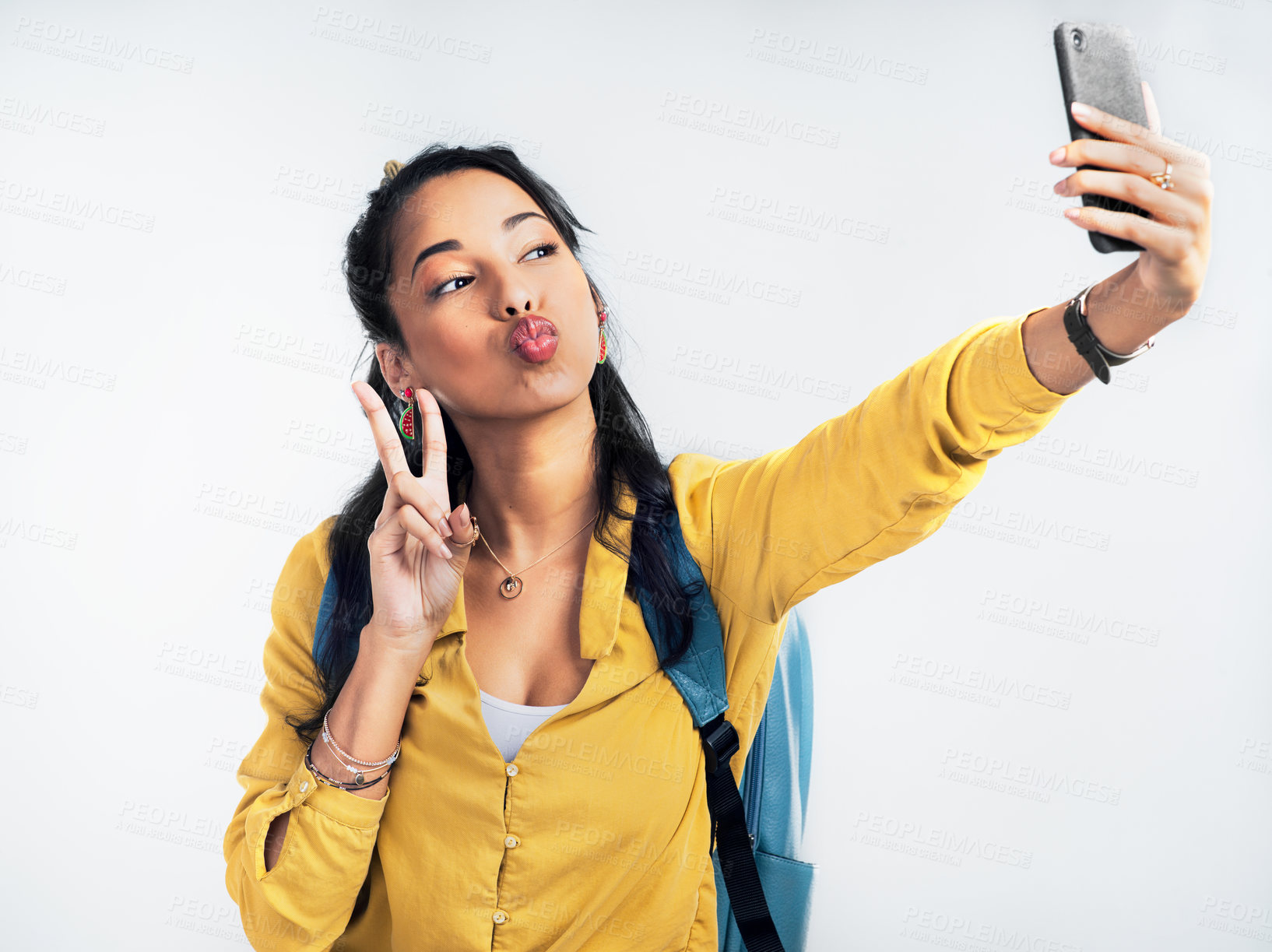 Buy stock photo Studio shot of a woman wearing a backpack and taking selfies against a white background