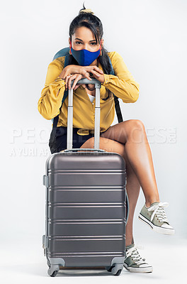 Buy stock photo Shot of a young woman wearing a mask while sitting on her suitcase