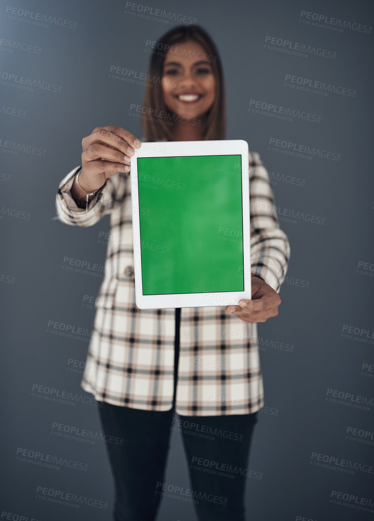 Buy stock photo Shot of an attractive young businesswoman standing against a grey background in the office and holding a digital tablet