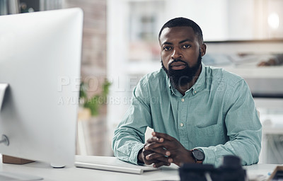 Buy stock photo Shot of a handsome young businessman sitting alone in his office and using his computer