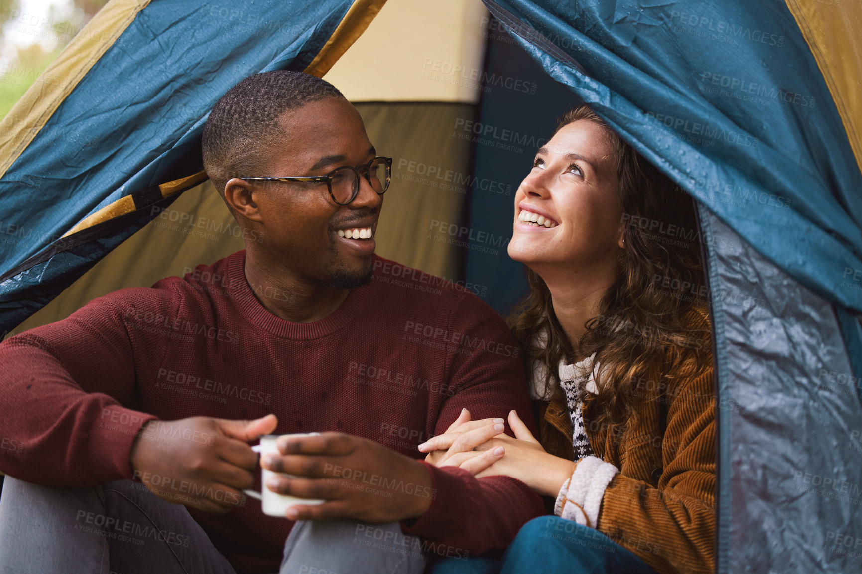 Buy stock photo Shot of a young couple drinking coffee while sitting in their tent