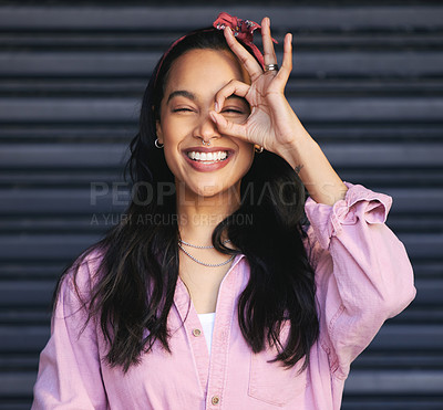 Buy stock photo Woman, portrait and ok gesture over eye, fun and playful with POV or lens for humor on dark background. Hand, vision or perspective with happy young model, silly or quirky for like emoji or sign