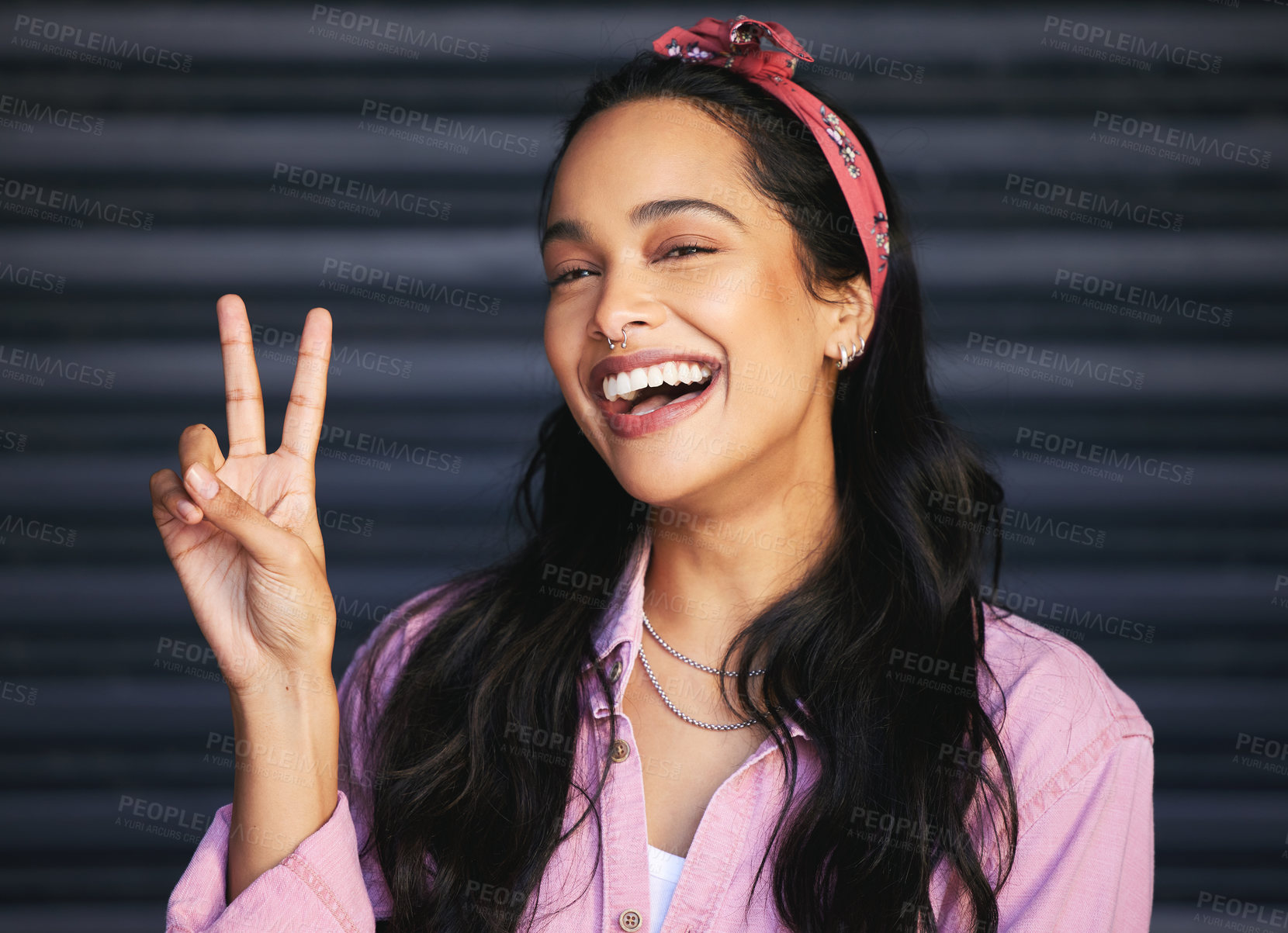 Buy stock photo Cropped portrait of an attractive young woman making the peace sign while posing against a grey background