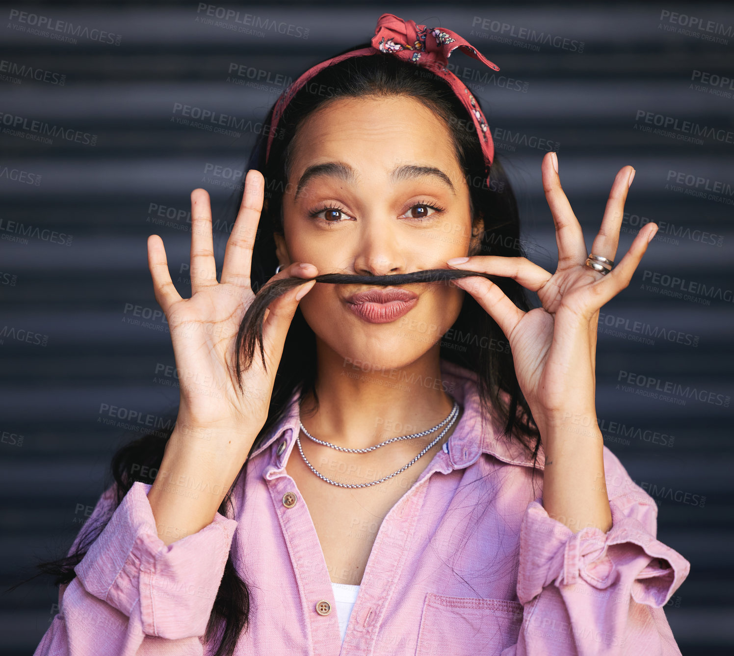 Buy stock photo Cropped portrait of an attractive young woman making a moustache with her hair while posing against a grey background