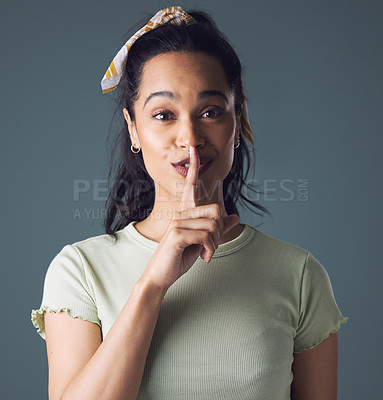 Buy stock photo Studio shot of a young woman posing with her finger over her lips