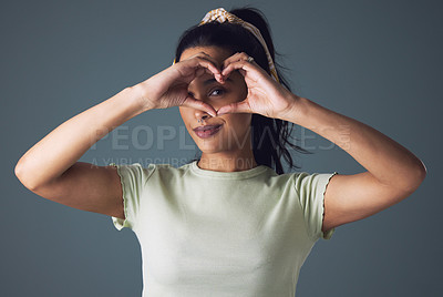 Buy stock photo Girl, fashion and eye with heart hand in studio on grey background in casual, style and gen z. Portrait, smile and cool with emoji or love sign and symbol for appreciation, support and positive