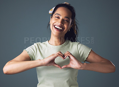 Buy stock photo Girl, fashion and happy with heart emoji in studio on grey background in casual, style and gen z. Portrait, smile and love sign for appreciation, support and affection with confidence and hands