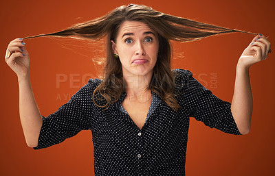 Buy stock photo Shot of an attractive young woman standing alone against a red background in the studio and touching her hair