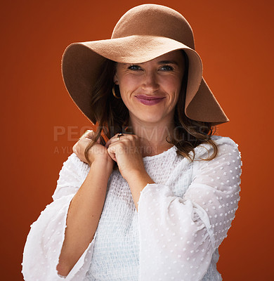 Buy stock photo Portrait, fashion and woman with hat for style, happy and stylish with trendy clothes or accessory on orange background. Face, feminine and elegant blouse for glamour, makeup and happy in a studio