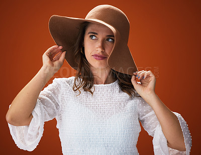 Buy stock photo Woman, hat and studio with thinking for fashion with fancy, trendy and summer outfit for vacation style inspiration. Stylish, brown background and trends with clothes for gorgeous with self esteem