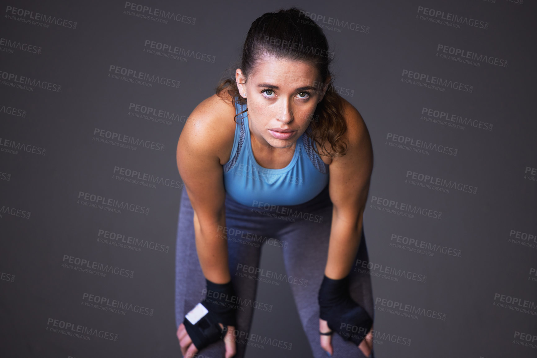 Buy stock photo Portrait of a sporty young woman catching her breath against a grey background