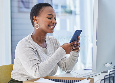 Buy stock photo Cellphone, desk and typing and black woman with smile, social media and scrolling for entertainment. Technology, computer and office for brand designer, distraction and employee on smartphone