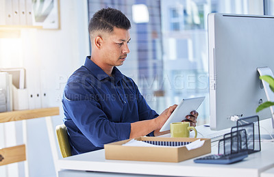 Buy stock photo Shot of a businessman using a digital tablet while sitting at his desk