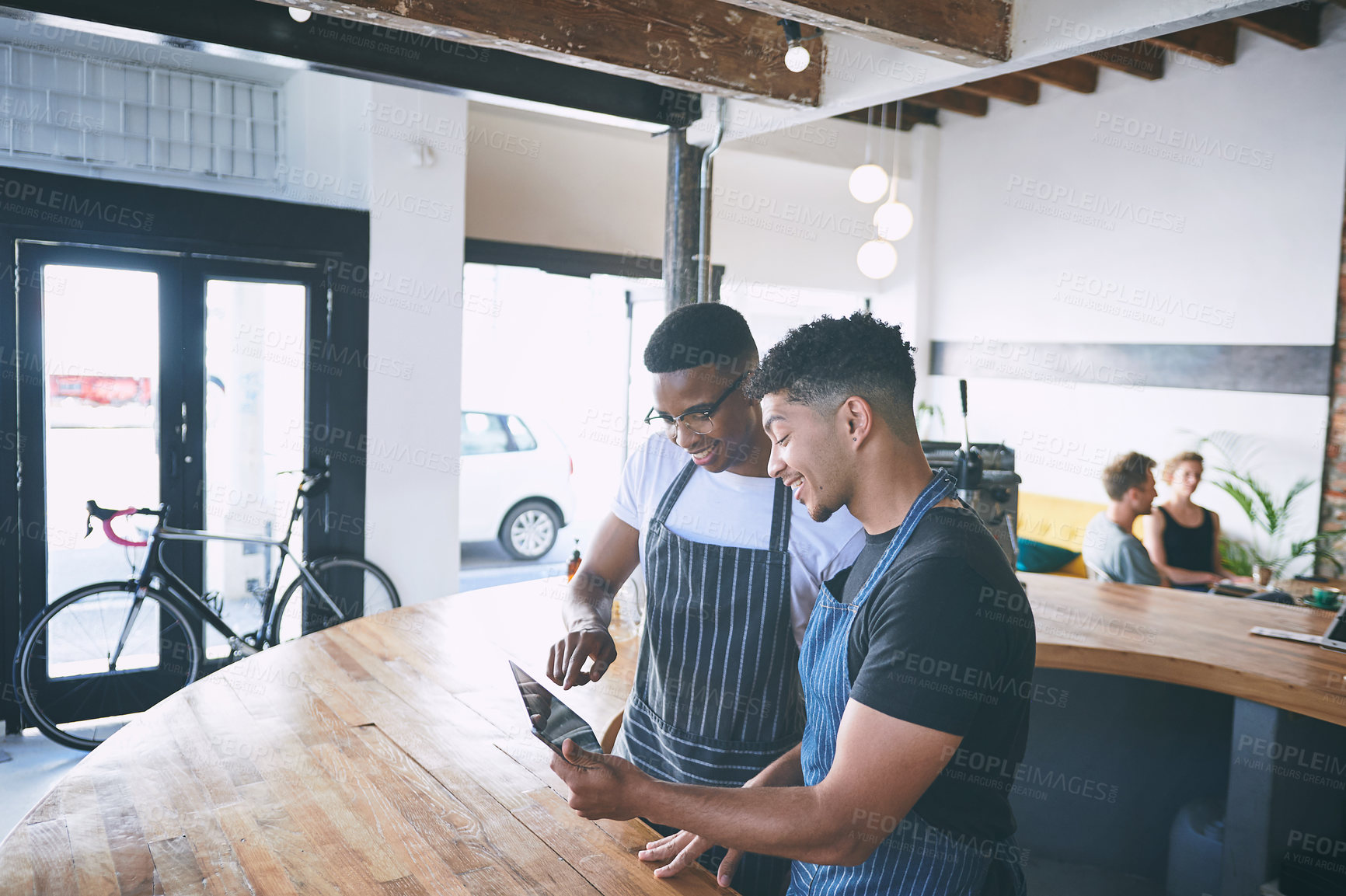 Buy stock photo Shot of two young men using a digital tablet while working in a cafe