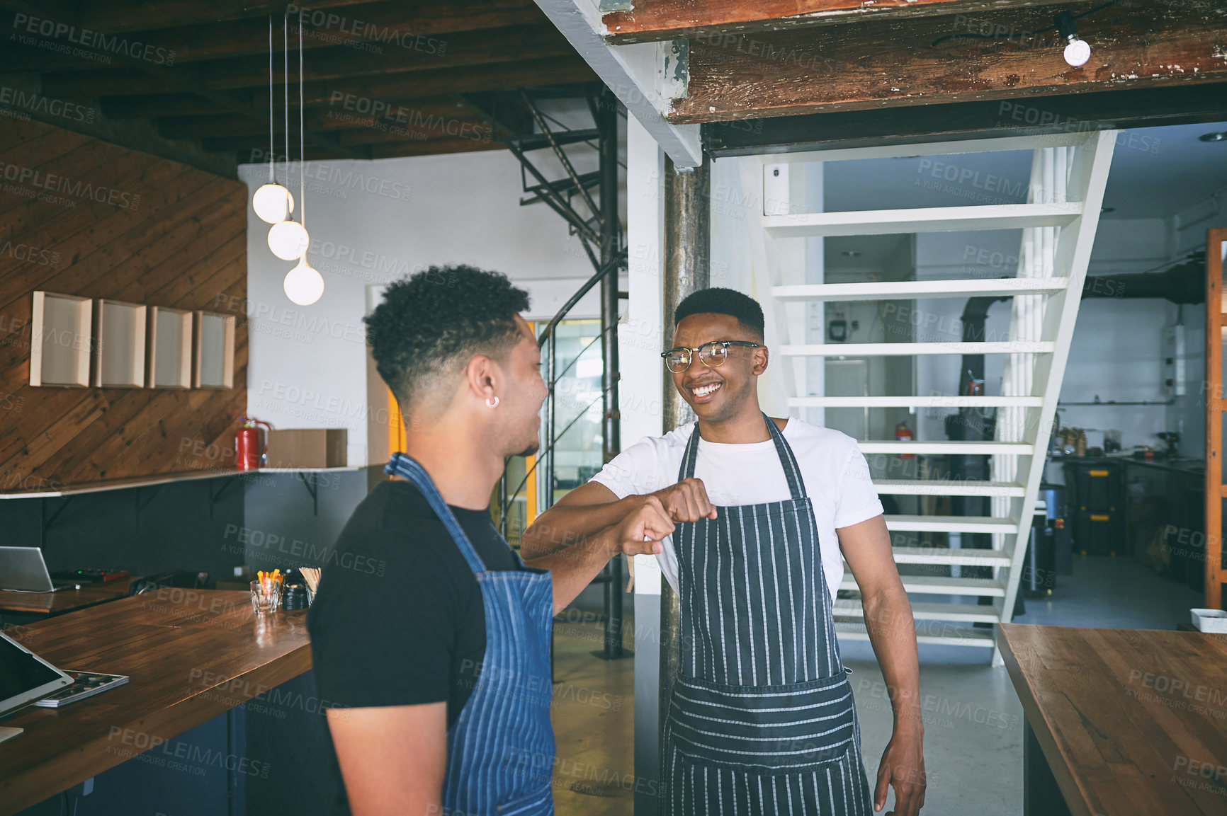 Buy stock photo Shot of two confident young men giving each other a fist bump while working in a cafe