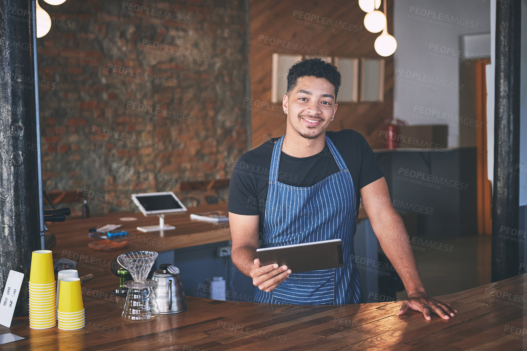 Buy stock photo Shot of a confident young man using a digital tablet while working in a cafe
