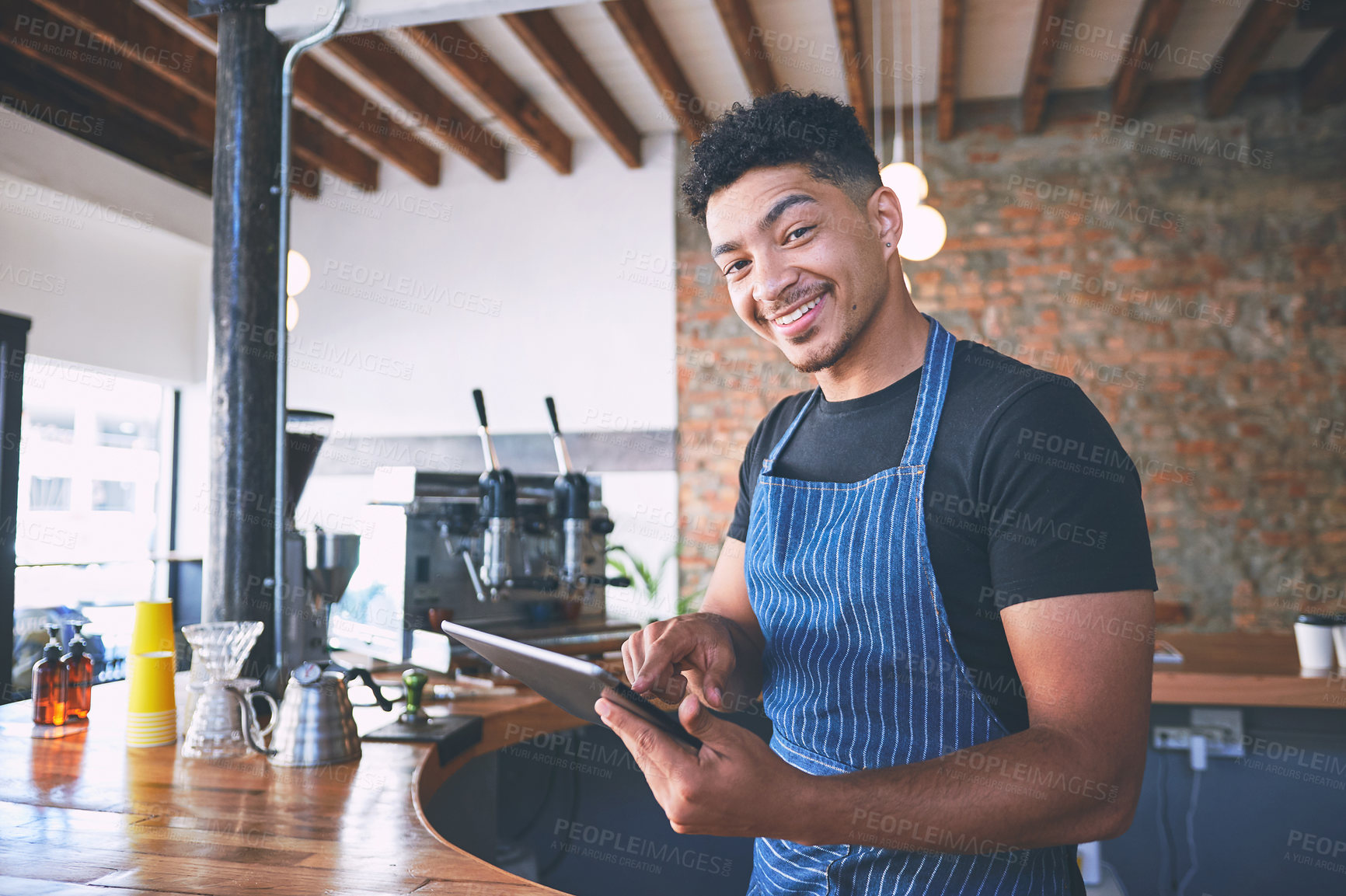 Buy stock photo Shot of a confident young man using a digital tablet while working in a cafe