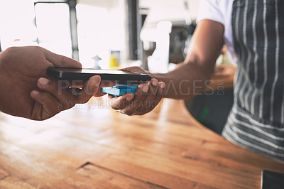 Buy stock photo Shot of an unrecognisable man using a smartphone to make a payment in a cafe