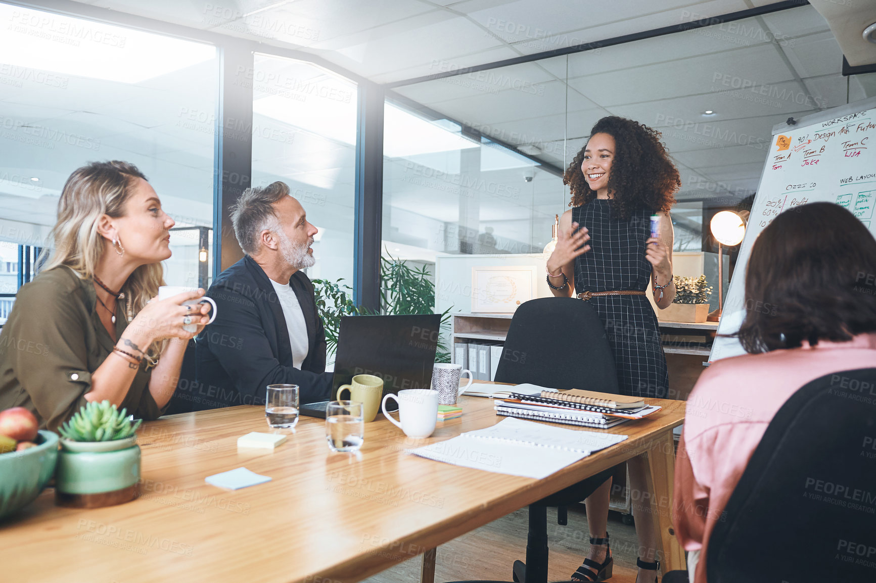 Buy stock photo Shot of a young businesswoman delivering a presentation to her coworkers in the boardroom of a modern office