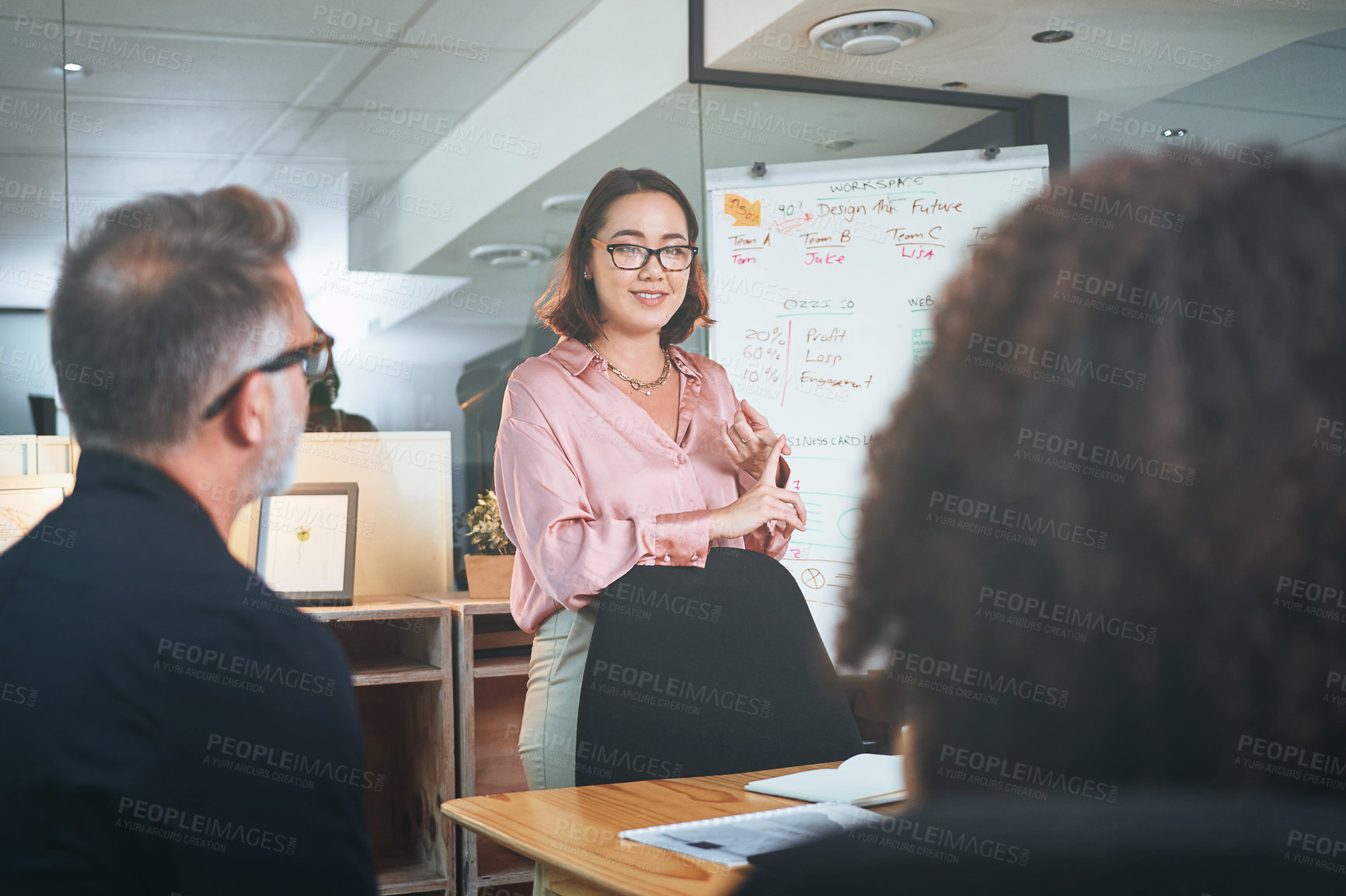 Buy stock photo Shot of a young businesswoman delivering a presentation to her coworkers in the boardroom of a modern office