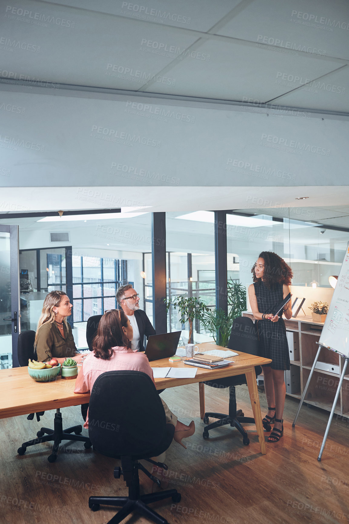 Buy stock photo Shot of a young businesswoman using a digital tablet delivering a presentation to her coworkers in a modern office