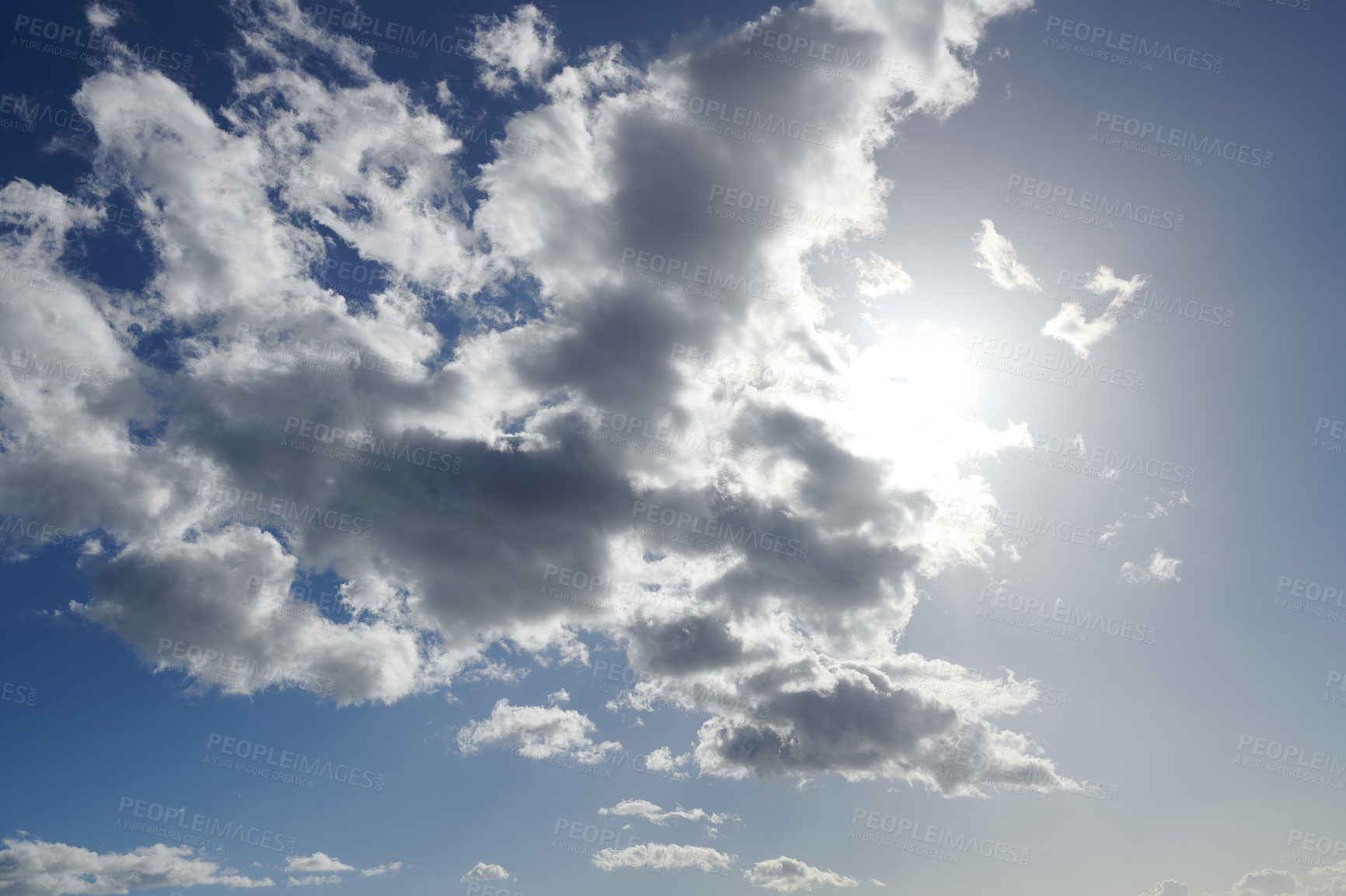 Buy stock photo Sun hiding behind clouds with blue sky. Beautiful sunshine from behind white and grey cumulus clouds at midday in summer. Serene view of nature's outdoor beauty high in space