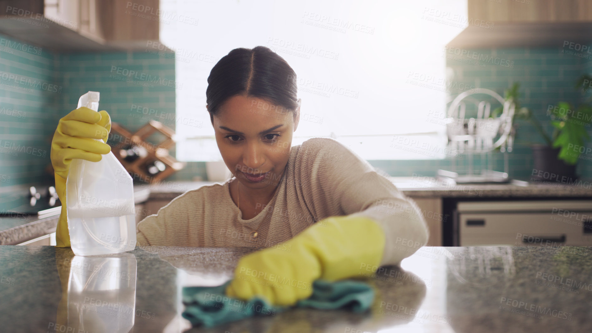 Buy stock photo Shot of a young woman scrubbing down her kitchen counter at home