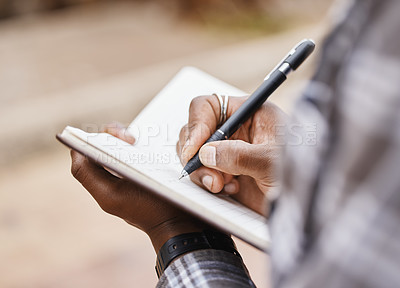 Buy stock photo Cropped shot of a man writing in a notebook on campus