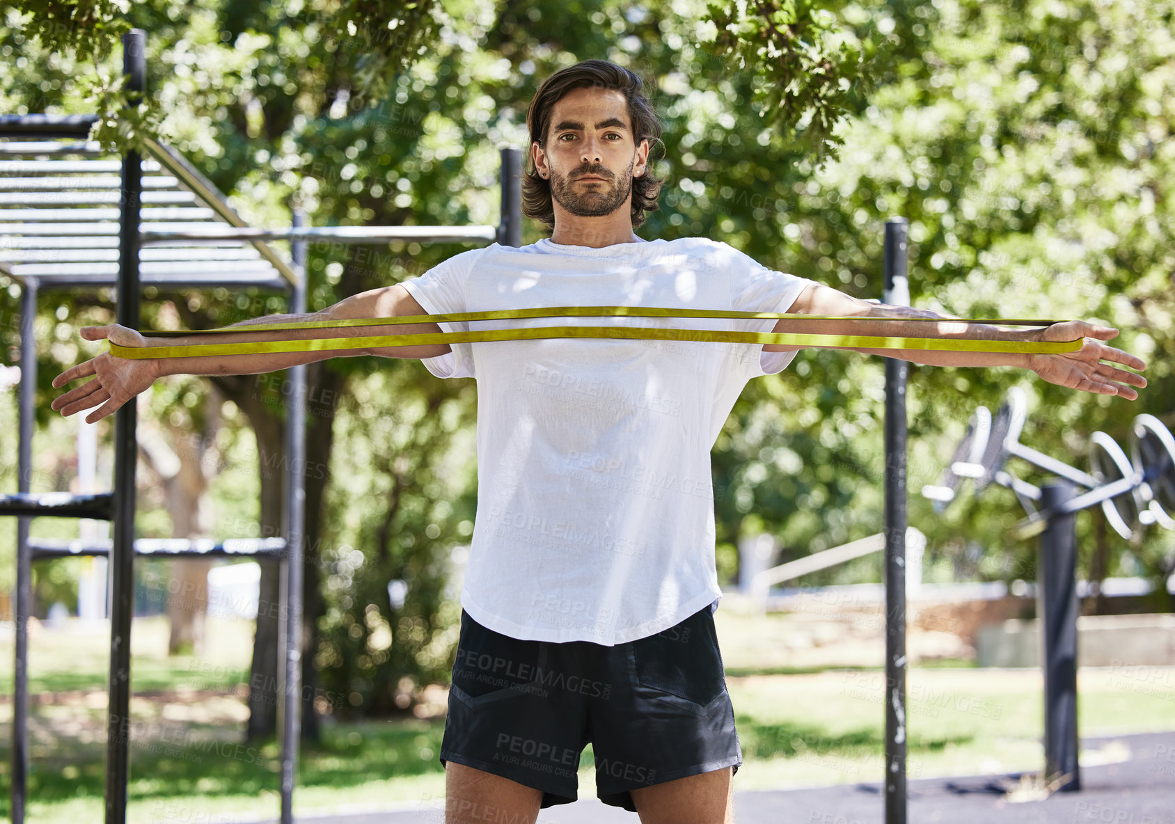 Buy stock photo Shot of a young man using his resistance band outside in the park