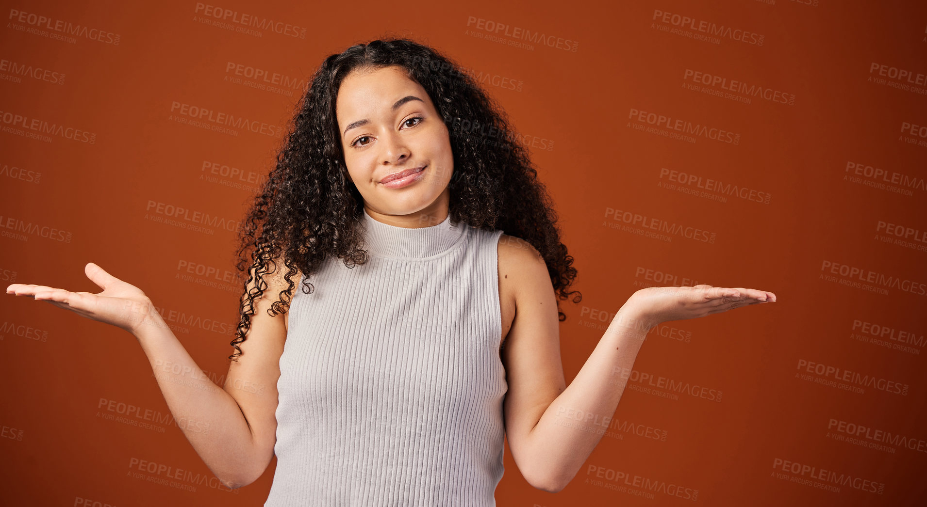 Buy stock photo Cropped portrait of an attractive young woman shrugging her shoulders in studio against a red background